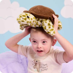 Little boy holding a Turtle Warmies on his head.