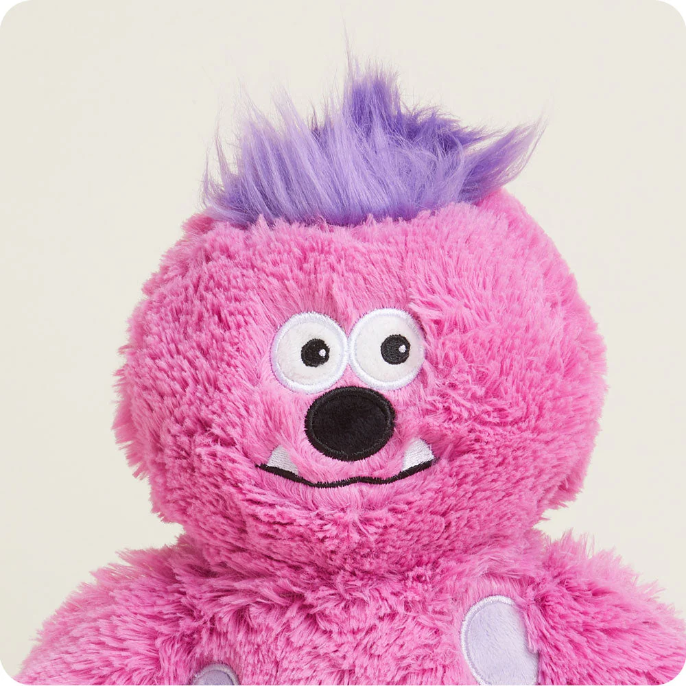 close up of face with purple hair, big embroidered eyes, oval black nose, wavy mouth with two triangle shaped teeth