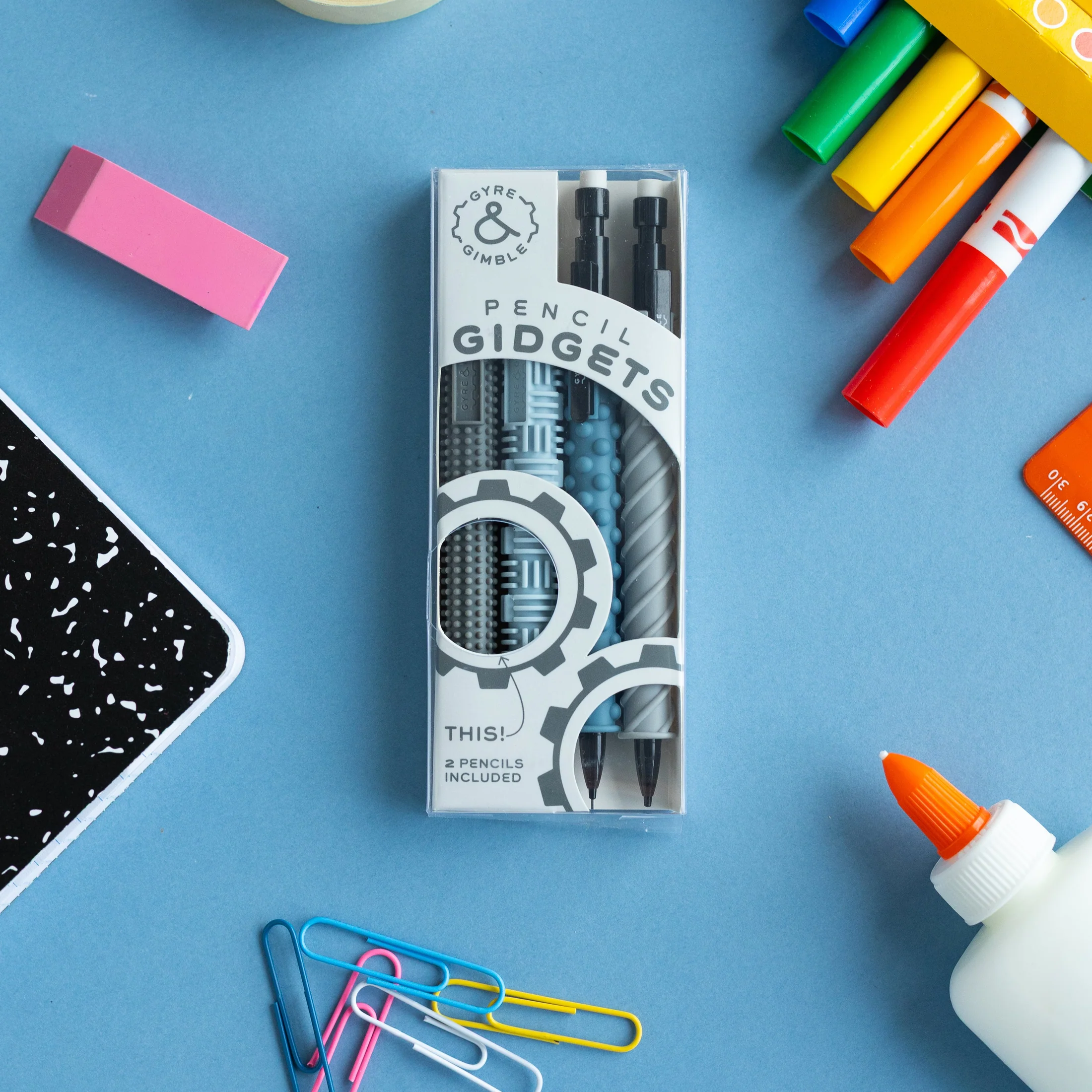 4 colorful silicone pencil gidgets and 2 mechanical pencils shown in box with other school supplies