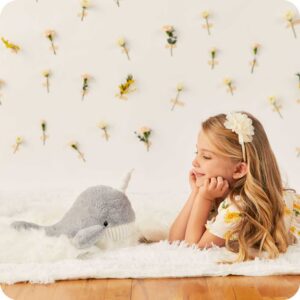 side view of girl facing narwhal stuffie, looking at eachother