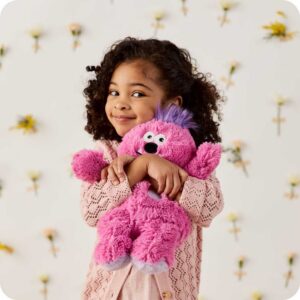 young girl hugs monster stuffie in arms