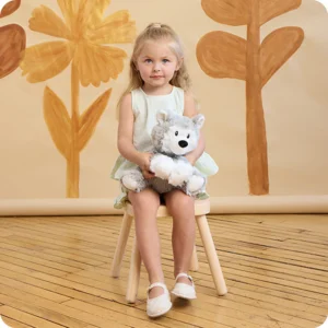 girl holding husky while sitting on a wooden stool