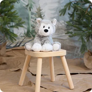husky stuffie on top of a wooden stool with pretend forest behind