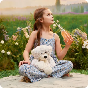 shows bear in the lap of a girl sipping soda outside