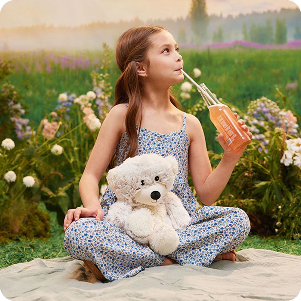 shows bear in the lap of a girl sipping soda outside