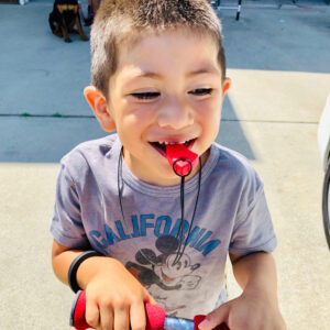 young boy chewing on red tooth necklace