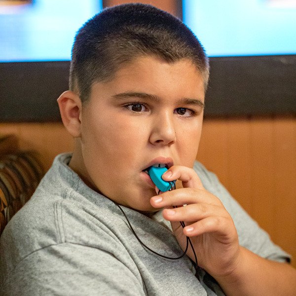 young boy chewing on tooth necklace