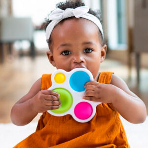 toddler holds white toy with 5 multicolor soft dots up to her mouth