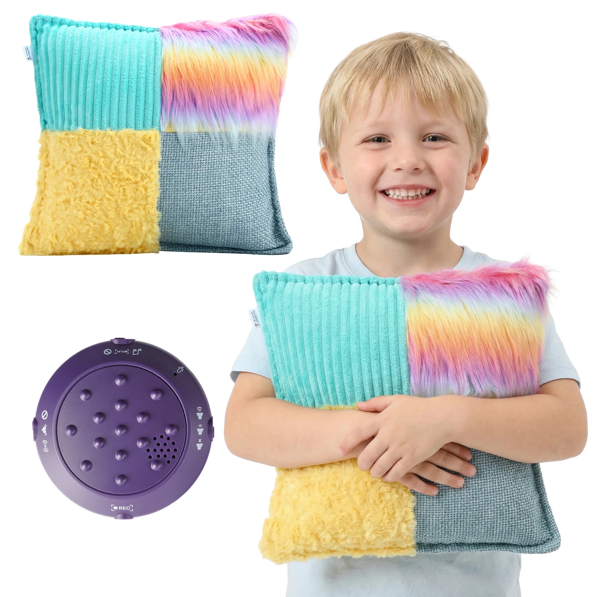 A young boy holds a square pillow that has fuzzy rainbow, blue, and yellow fabric