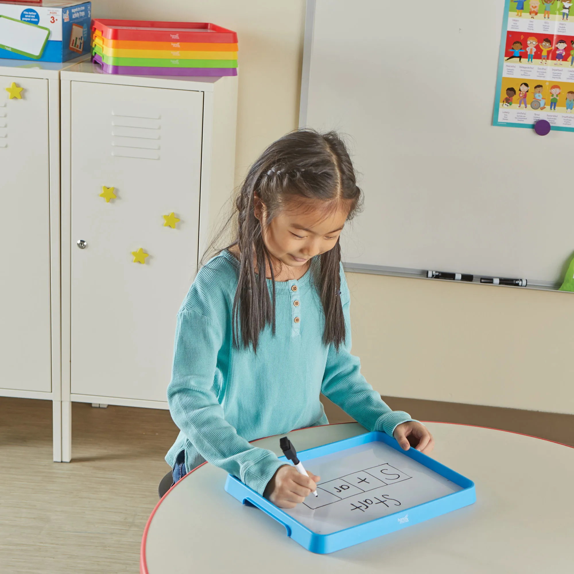 child writing with a dry erase marker on one of the boards