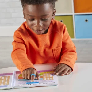 young boy reading with a blue highlighter that highlights the word on the page, attached to a ring on his finger