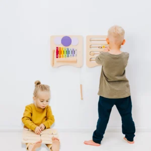 child playing with two modules on a wall, and another child on the floor playing with a third