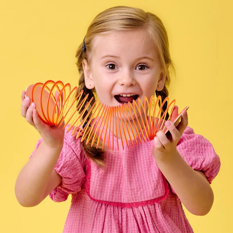 girl playing with coiled toy that has flat ends on either side