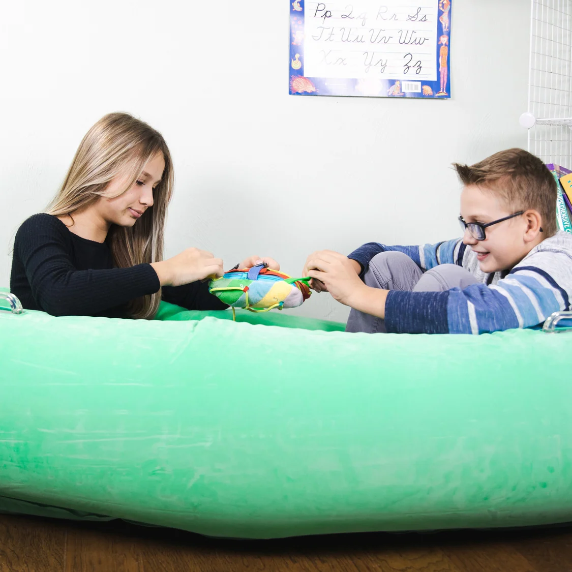 a teen girl and a boy sitting together in the pod playing with a soft toy