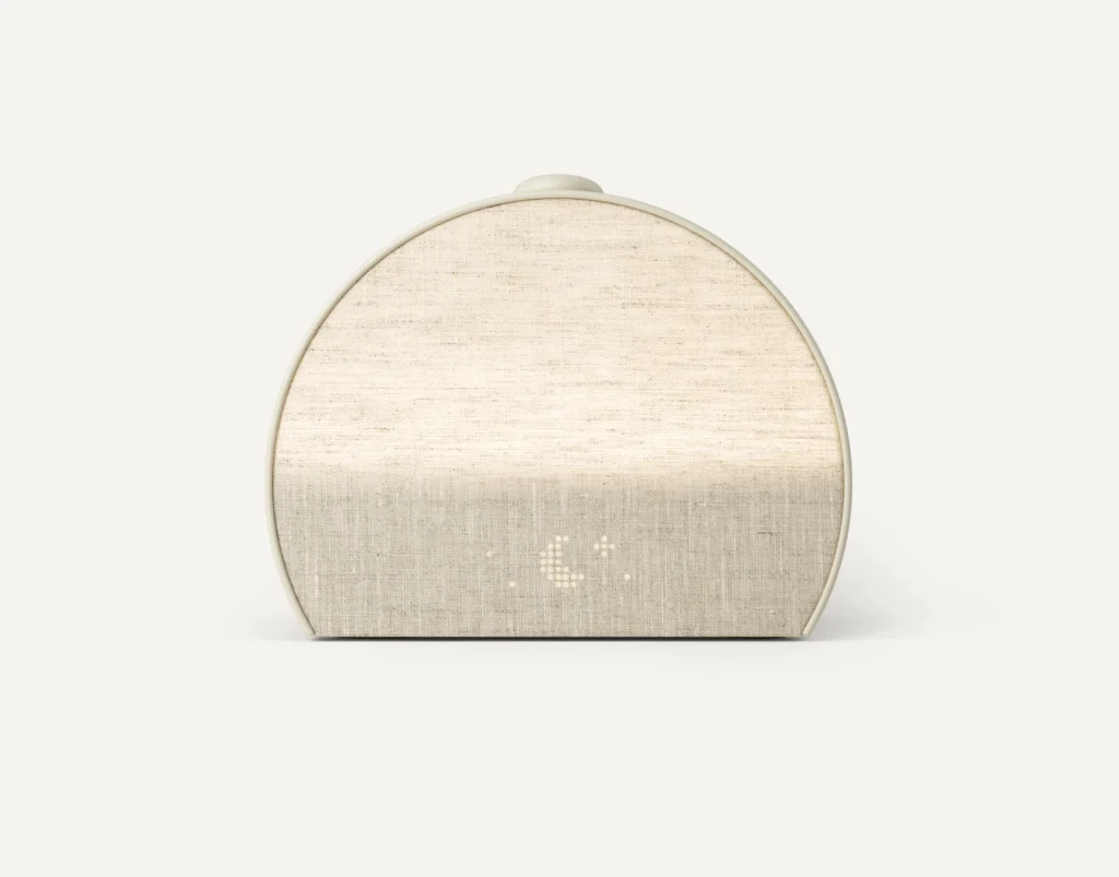 beige colored alarm clock is about 2/3 of a full circle shape with a fabric face