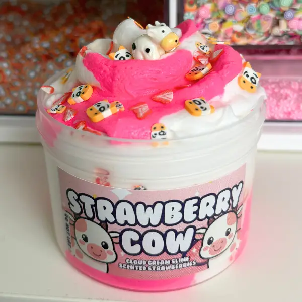 jar of strawberry cow slime has white and pink slimes with small cow sprinkles and a big cow charm