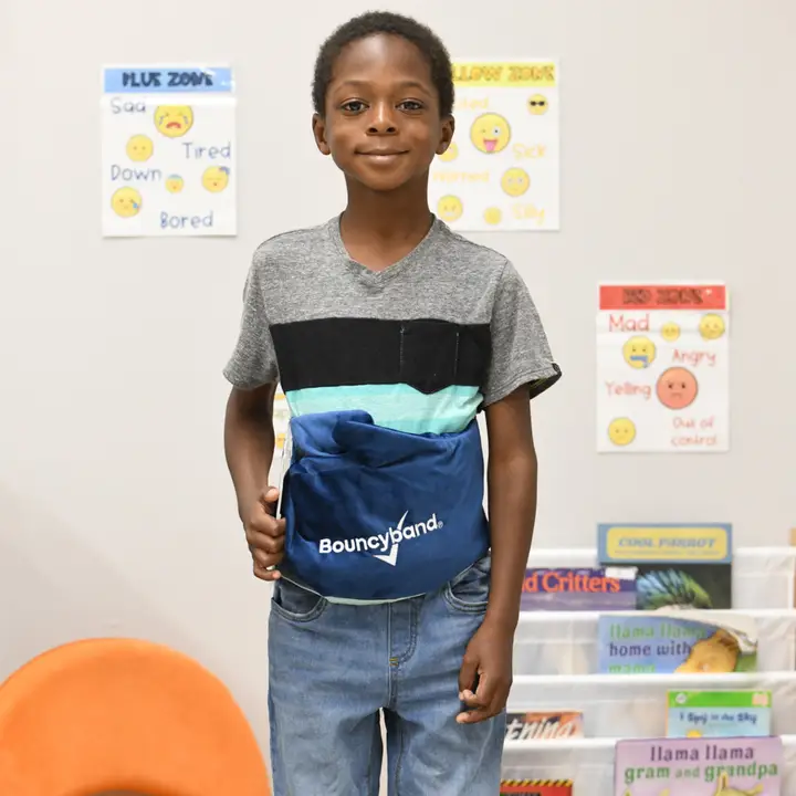 child wearing blue belt around waist in a classroom