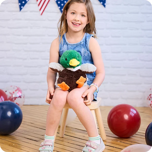 child on stool with duck stuffie on her lap