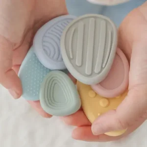 two hands hold 6 pastel colored silicone worry stones with different shapes, sizes and textures