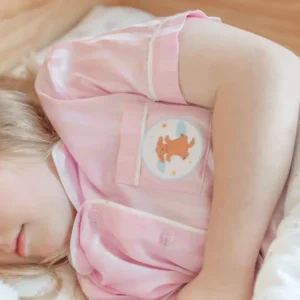 a child lying down in bed with a circular sticker on her pajama pocket